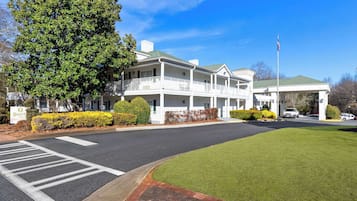 Classic hotel with a central entrance, well-manicured lawn, and parking area.