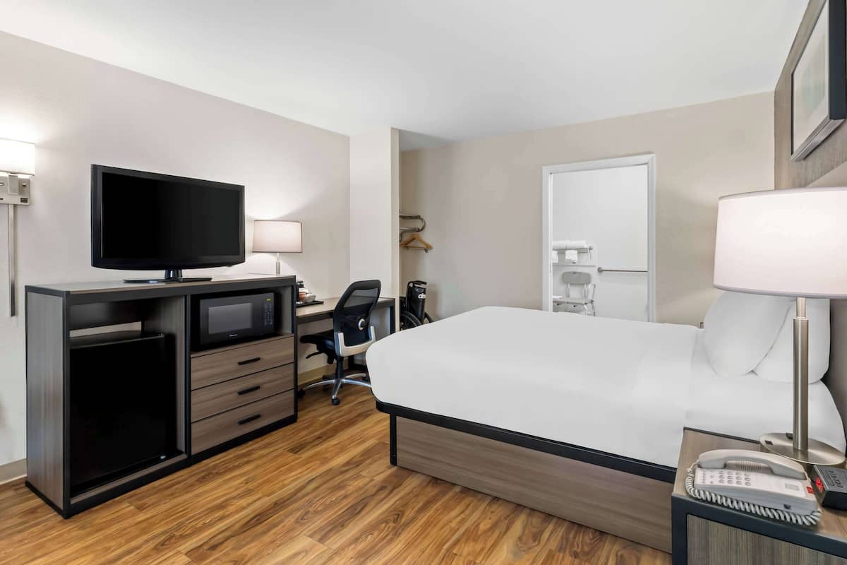 Habitación de hotel con cama, escritorio, silla, televisión y teléfono.