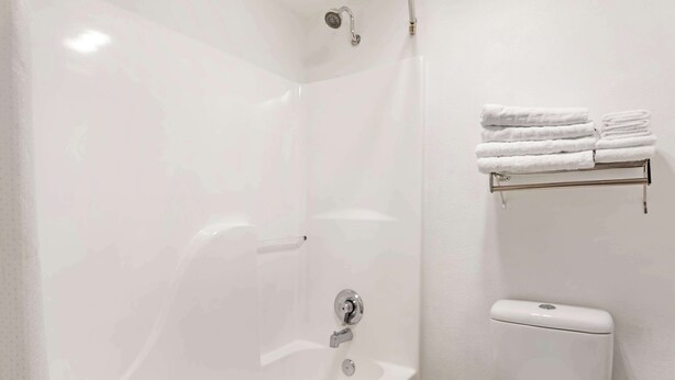 A bathroom with a white bathtub, a toilet, and a towel rack with folded towels.
