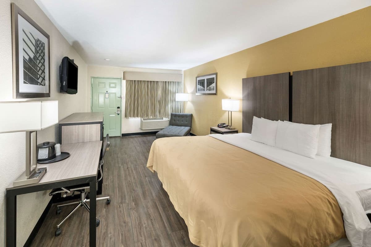 Una camera d'albergo con un letto, una scrivania, una sedia e un televisore.