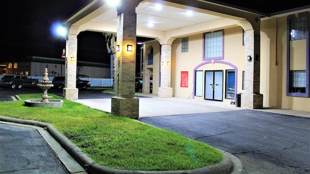 A hotel with a covered parking area, a fountain, and a well-maintained lawn.