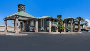 A hotel with a central entrance, a clock tower, and a sign indicating "Quality Inn".