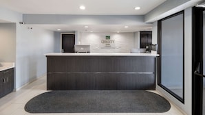A reception area with a modern design, featuring a reception desk, a wall-mounted sign, and a large window.
