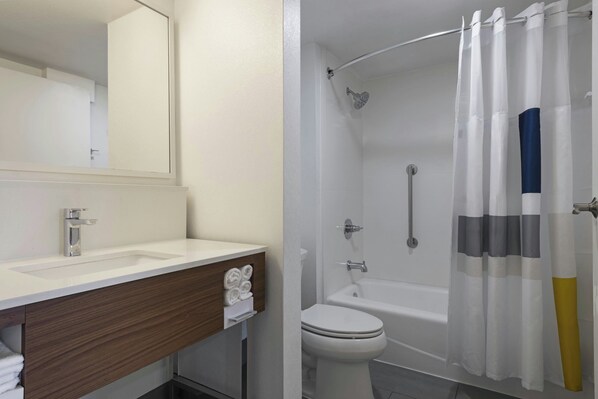 A bathroom with a white sink, a mirror, a toilet, and a shower with a white curtain.