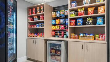 Un espace proposant des distributeurs automatiques de collations et de boissons, avec un assortiment varié de produits.