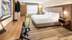 Een hotelkamer met een bed, een bureau met stoel, een televisie en een raam.