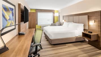 Une chambre d’hôtel avec un lit, un bureau et une chaise, une télévision et une fenêtre.