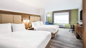 Una habitación de hotel con dos camas, un escritorio, una silla, un televisor y una ventana.