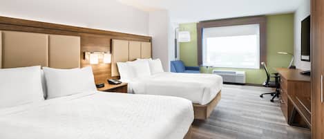 A hotel room with two beds, a desk, a chair, a TV, and a window.