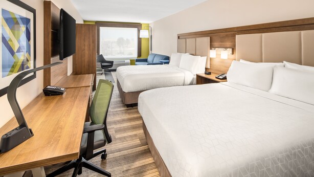 Een hotelkamer met twee bedden, een bureau met stoel, een televisie en een raam met uitzicht.