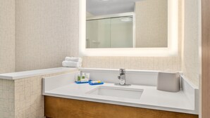 Een moderne badkamer met een grote spiegel, een wit wastafelmeubel en een douchecabine van glas.