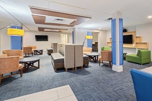 Een hotel lobby met zithoeken, een flatscreen televisie en een receptiebalie.