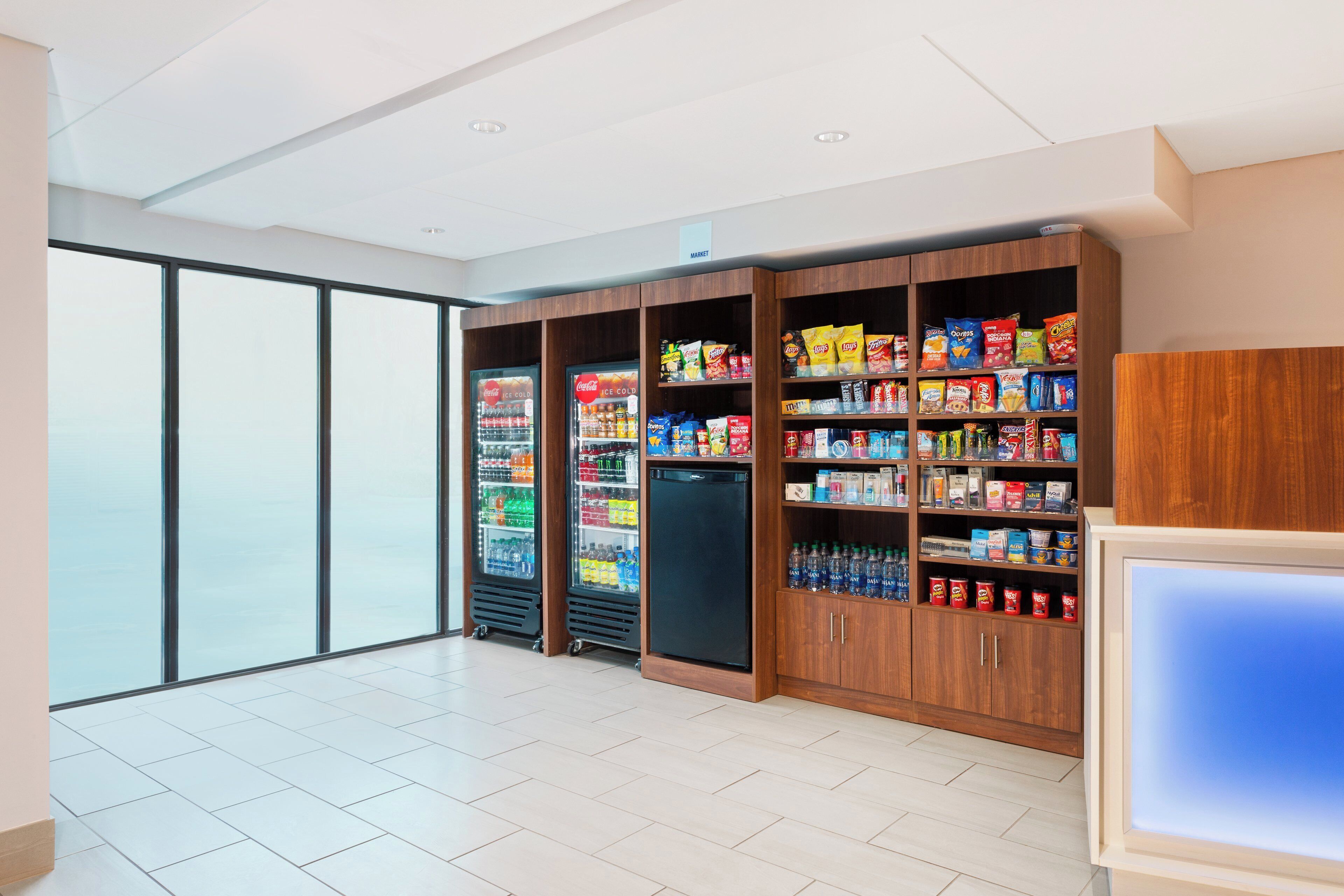 A spacious room with a large window, vending machines, and a refrigerator stocked with snacks.