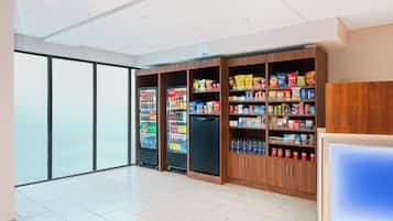 A spacious room with a large window, vending machines, and a refrigerator stocked with snacks.