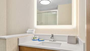 Un baño moderno con un espejo grande, un lavamanos blanco y una zona de ducha.