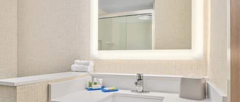 Un baño moderno con un espejo grande, un lavamanos blanco y una zona de ducha.