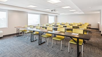 Un salón de conferencias con una larga mesa, varias sillas y un proyector.
