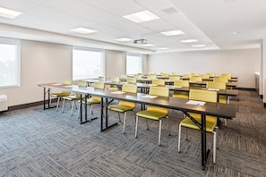 A conference room with a long table, multiple chairs, and a projector.