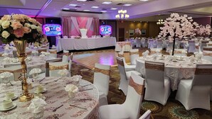 A banquet hall with round tables set for a formal event, featuring white tablecloths and gold accents.