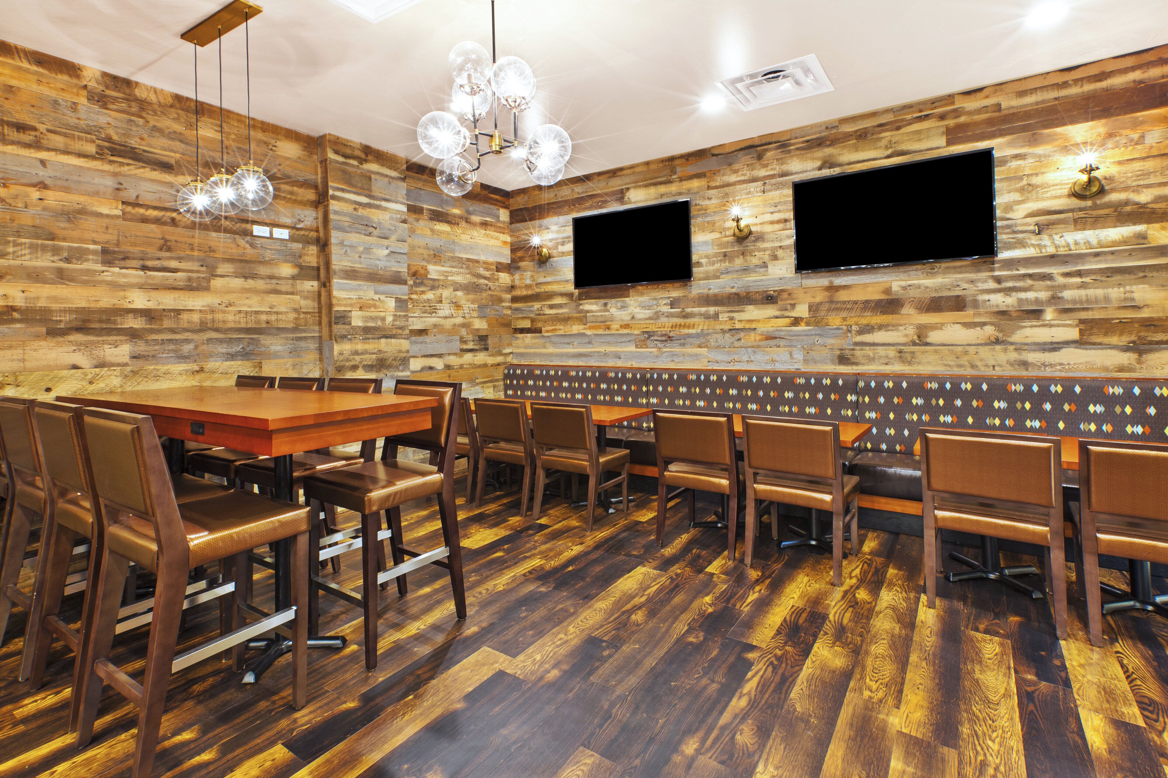 A restaurant with a wooden wall design, multiple seating arrangements, and a flat-screen TV mounted on the wall.