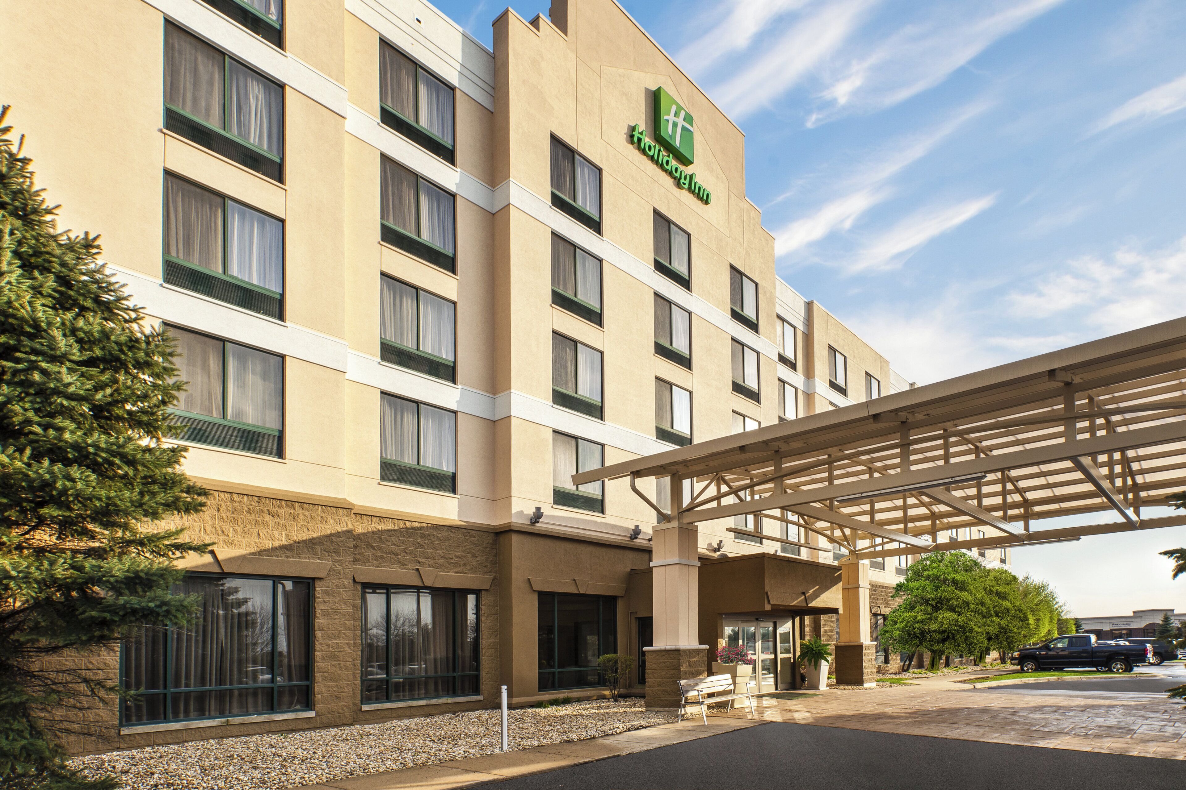 A hotel with a covered entrance, multiple windows, and a sign indicating it is a Holiday Inn.