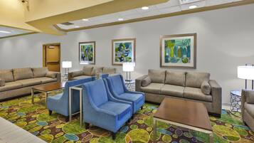 A hotel lobby with multiple seating areas, including sofas and armchairs, and a patterned carpet.