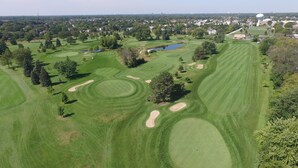 A golf course with sand bunkers, water hazards, and a pond.