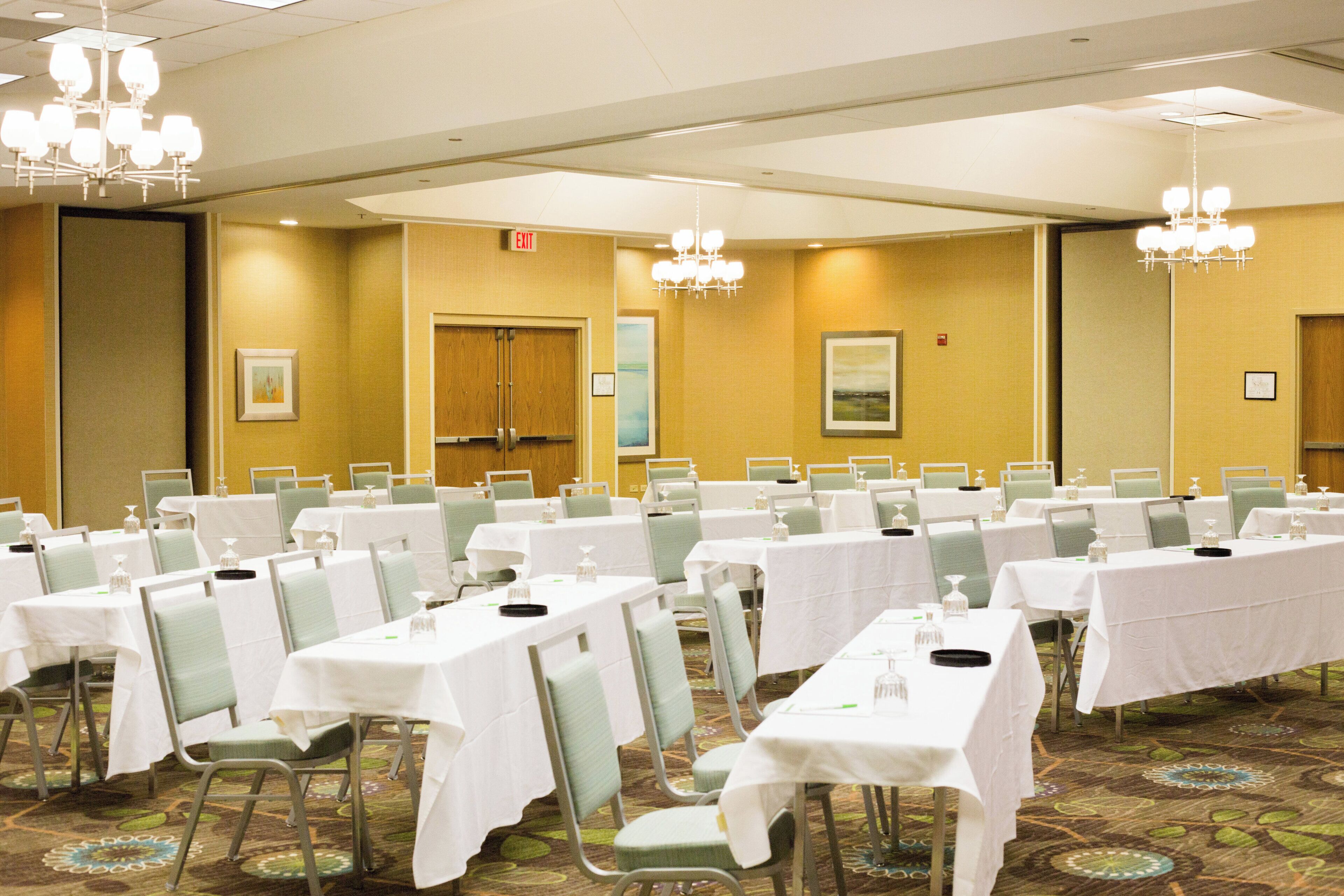 A conference room with multiple tables and chairs, equipped with nameplates and water bottles.