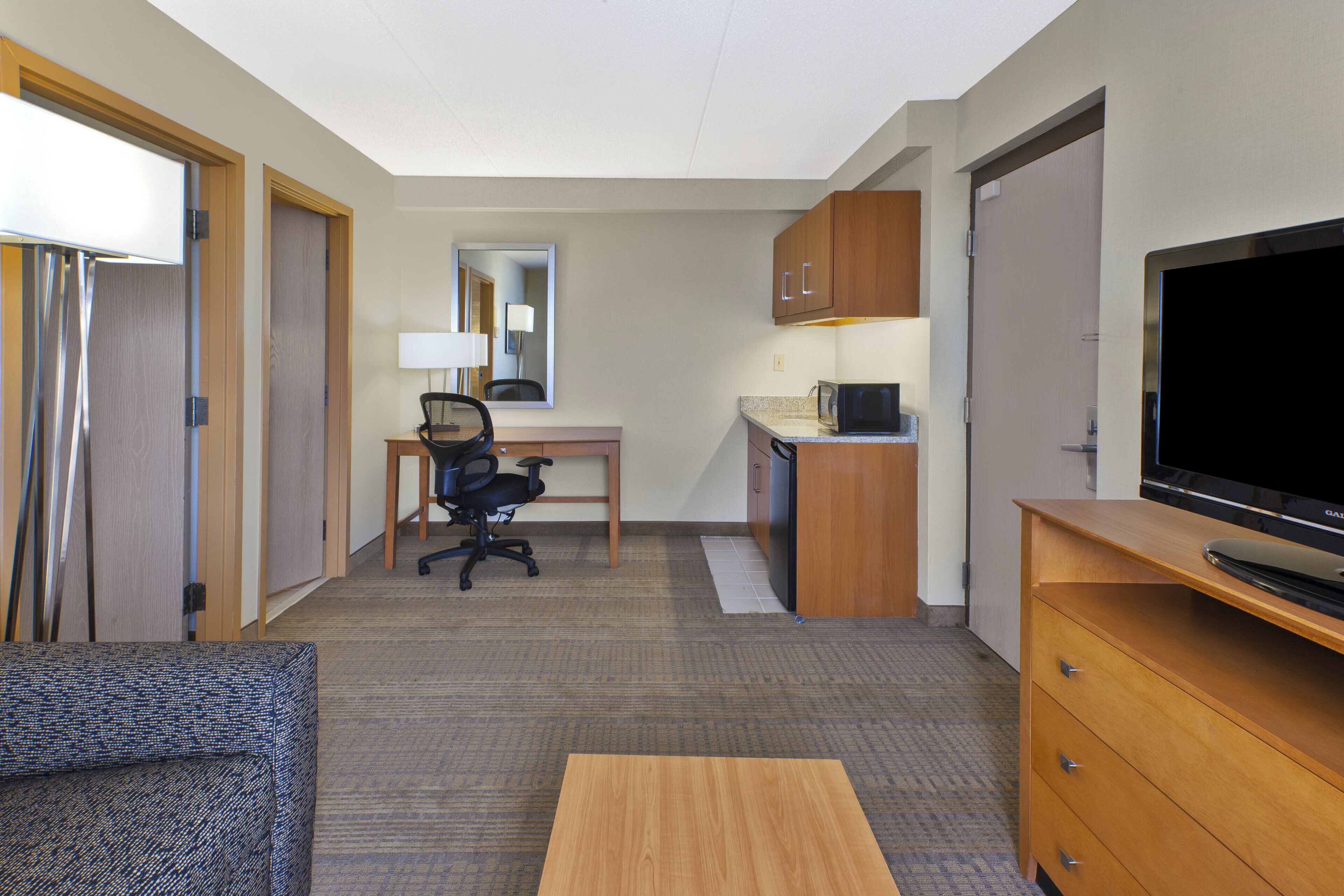 A hotel room with a bed, a desk, a chair, a television, and a wardrobe.