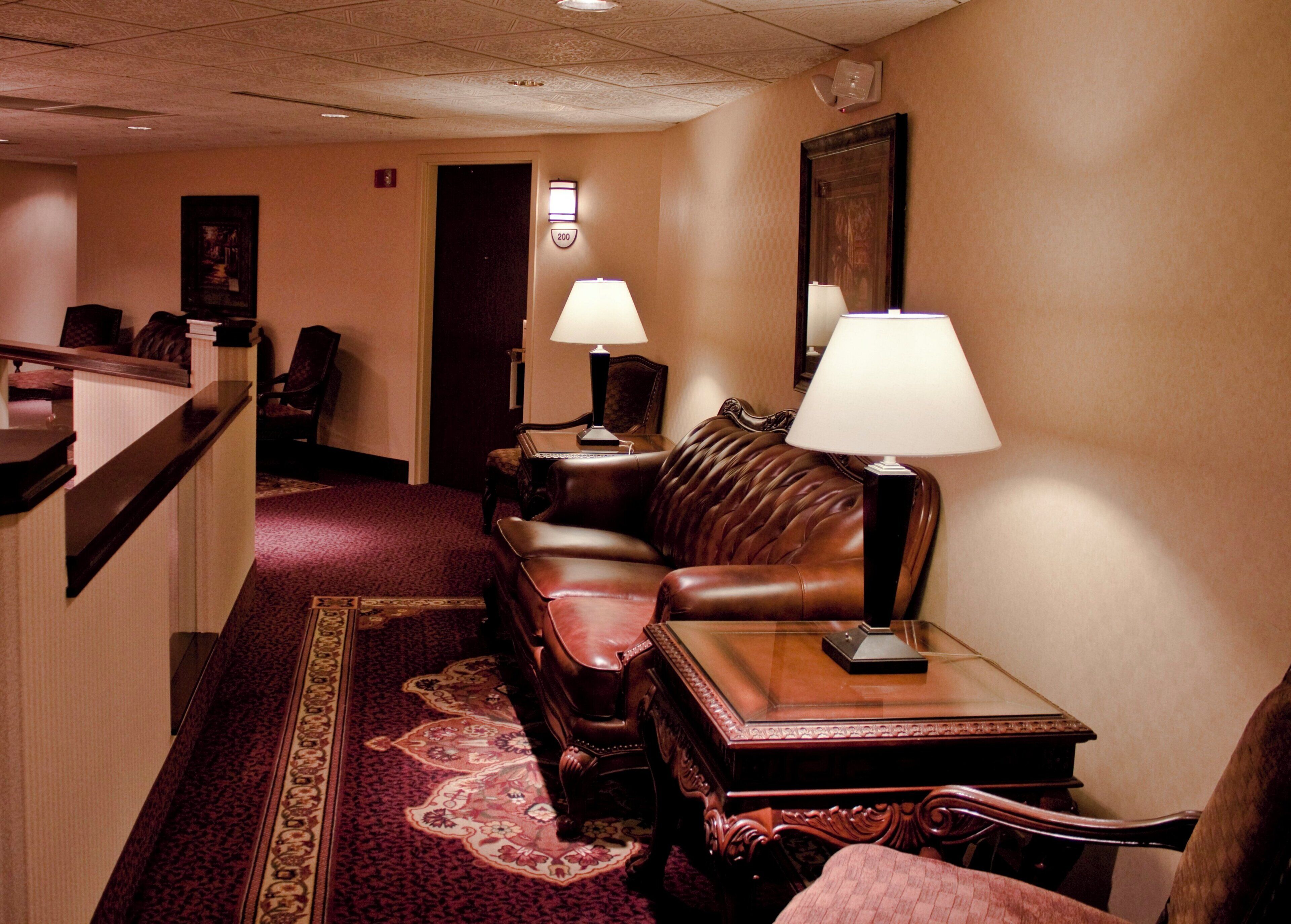 A hotel lobby with a reception desk, a leather sofa, two lamps, a carpeted floor, and a door marked '200'.