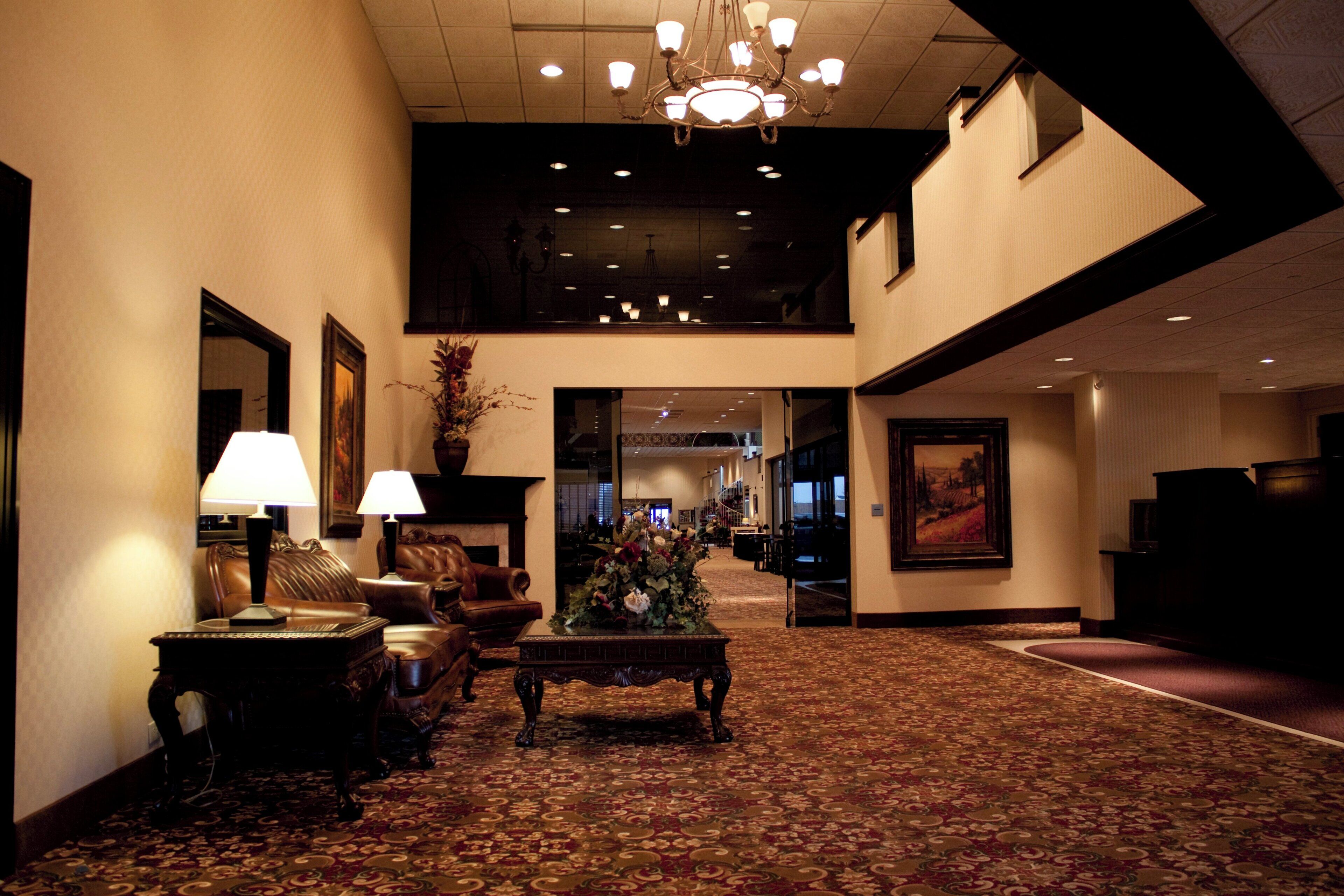 A hotel lobby with a chandelier, sofas, a coffee table, and a carpeted floor.