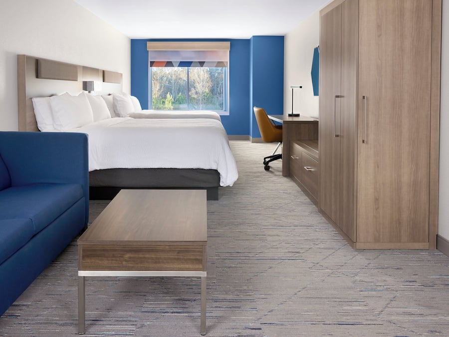 Una habitación de hotel con una cama, un sofá azul, un escritorio de madera y un armario.