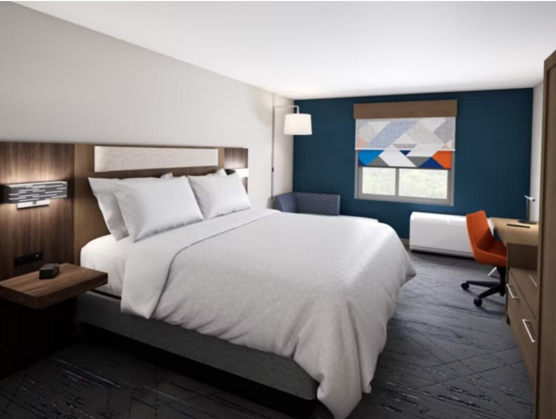 Une chambre d’hôtel moderne avec un grand lit, un bureau et une chaise.