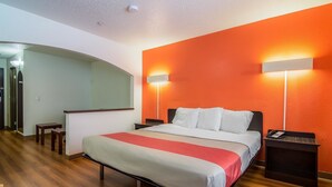 Une chambre d’hôtel avec un lit, des tables de chevet, un bureau et un miroir.