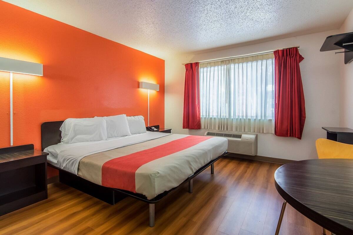 A hotel room with a bed, bedside tables, a desk, and a chair.