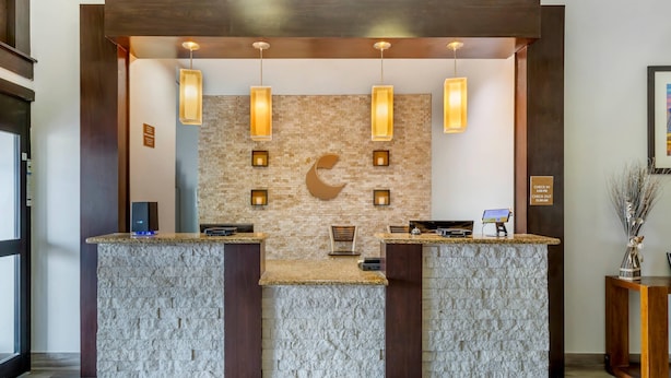 A reception desk with a stone facade, pendant lighting, and a check-in/out sign. - Comfort Inn & Suites Houston FM1960 - Champions (Houston)