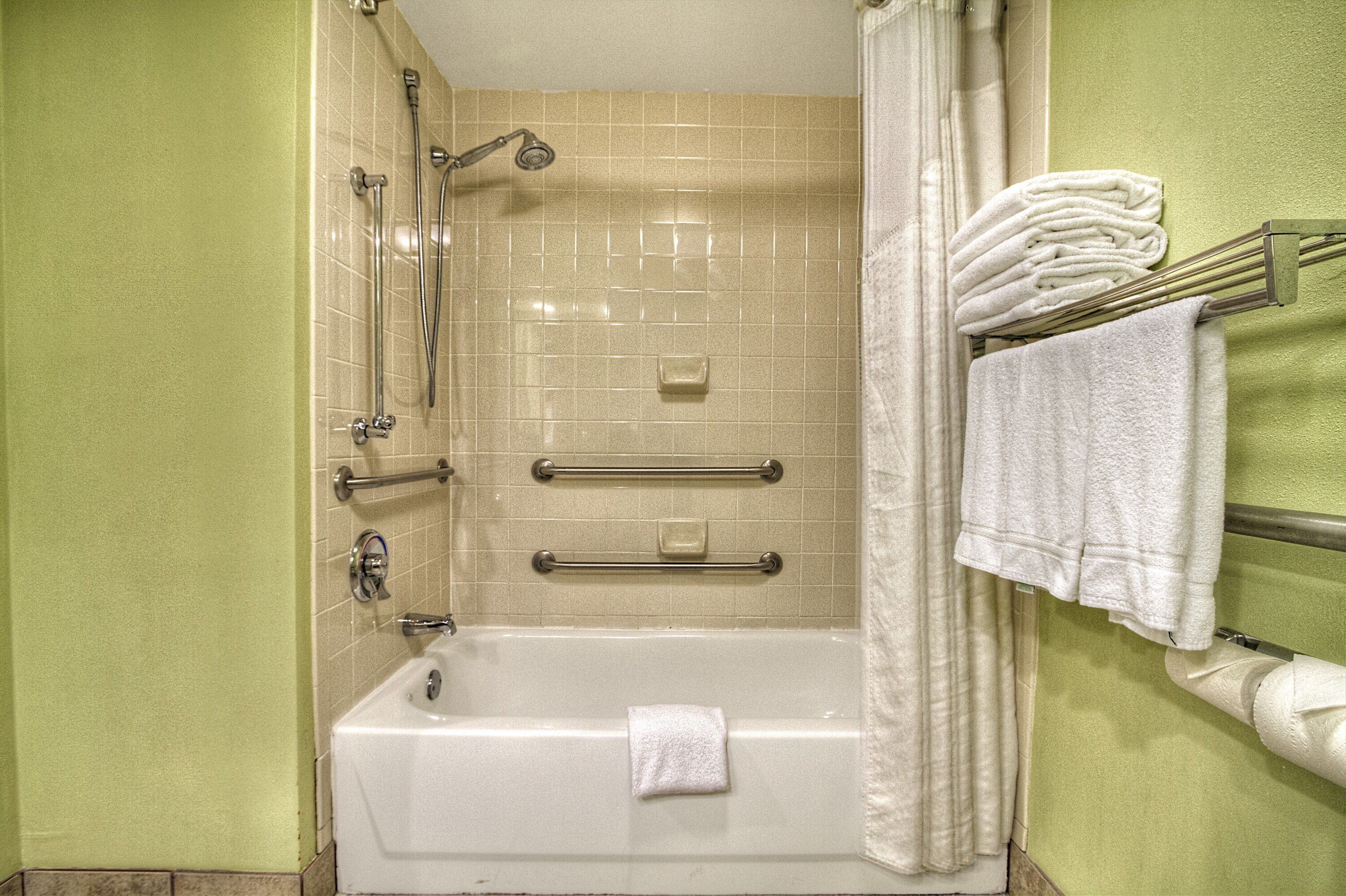A bathroom with a bathtub, a shower, and a towel rack with towels.