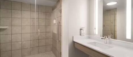 A modern bathroom with a glass-enclosed shower, a large mirror, and a wooden vanity.