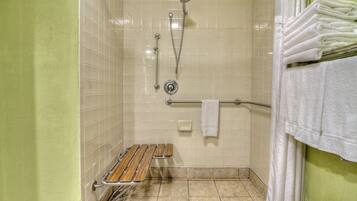 A shower area with a wooden bench, a towel rack, and a hand shower.