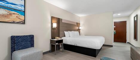 A hotel room with a bed, a nightstand, a chair, a desk, and a painting on the wall.
