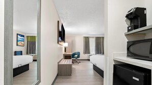 A hotel room with a bed, a desk, a chair, a microwave, and a coffee maker. - Quality Inn Sandersville (Sandersville)