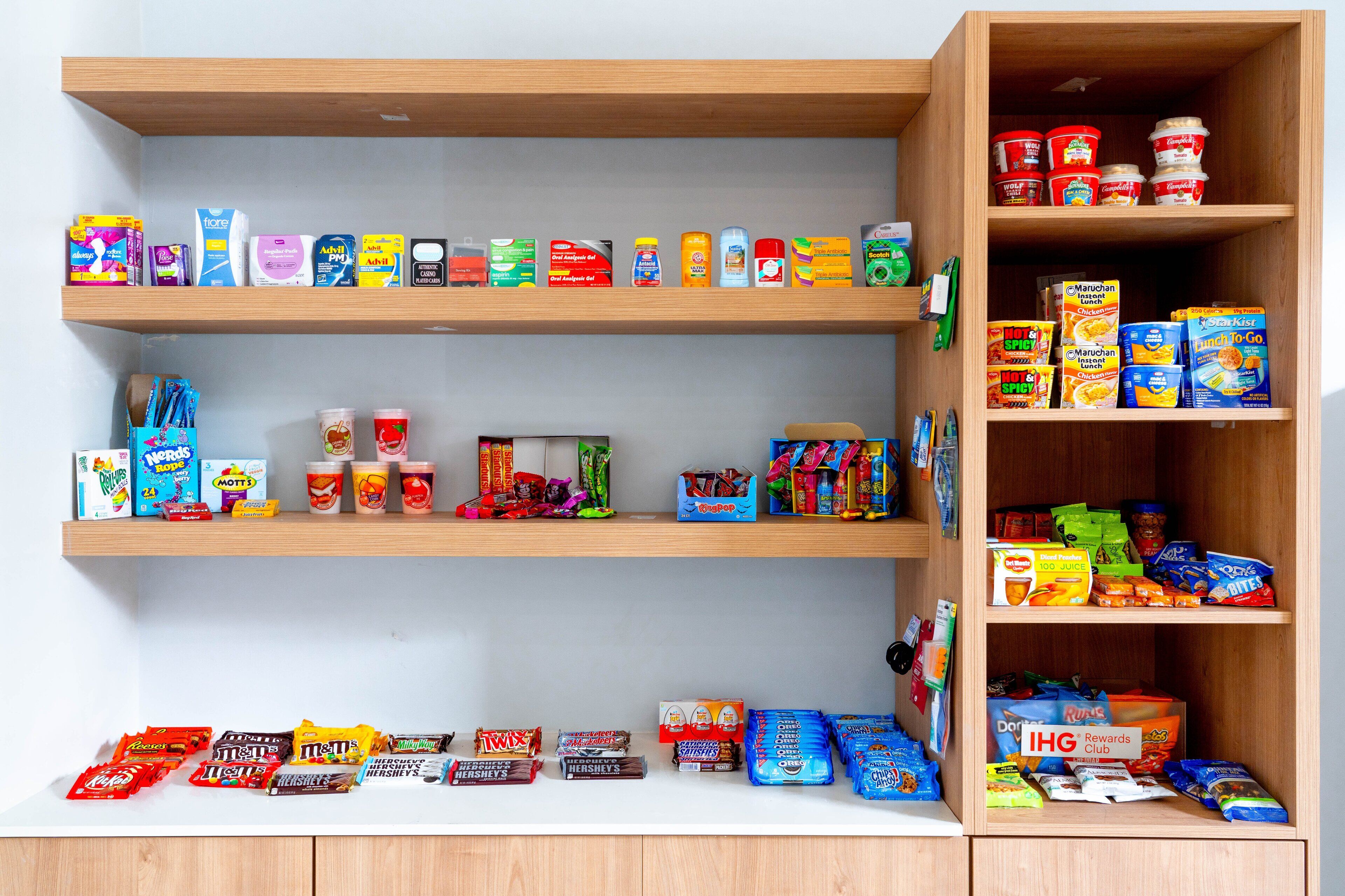 Une étagère remplie de diverses collations et boissons, notamment des bonbons, des chips et des boissons.
