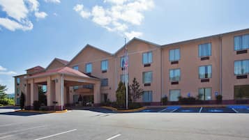 Een meerhoog hotel met een overdekte ingang, een parkeerplaats met mindervalidenparkeerplaatsen, en een Amerikaanse vlag.