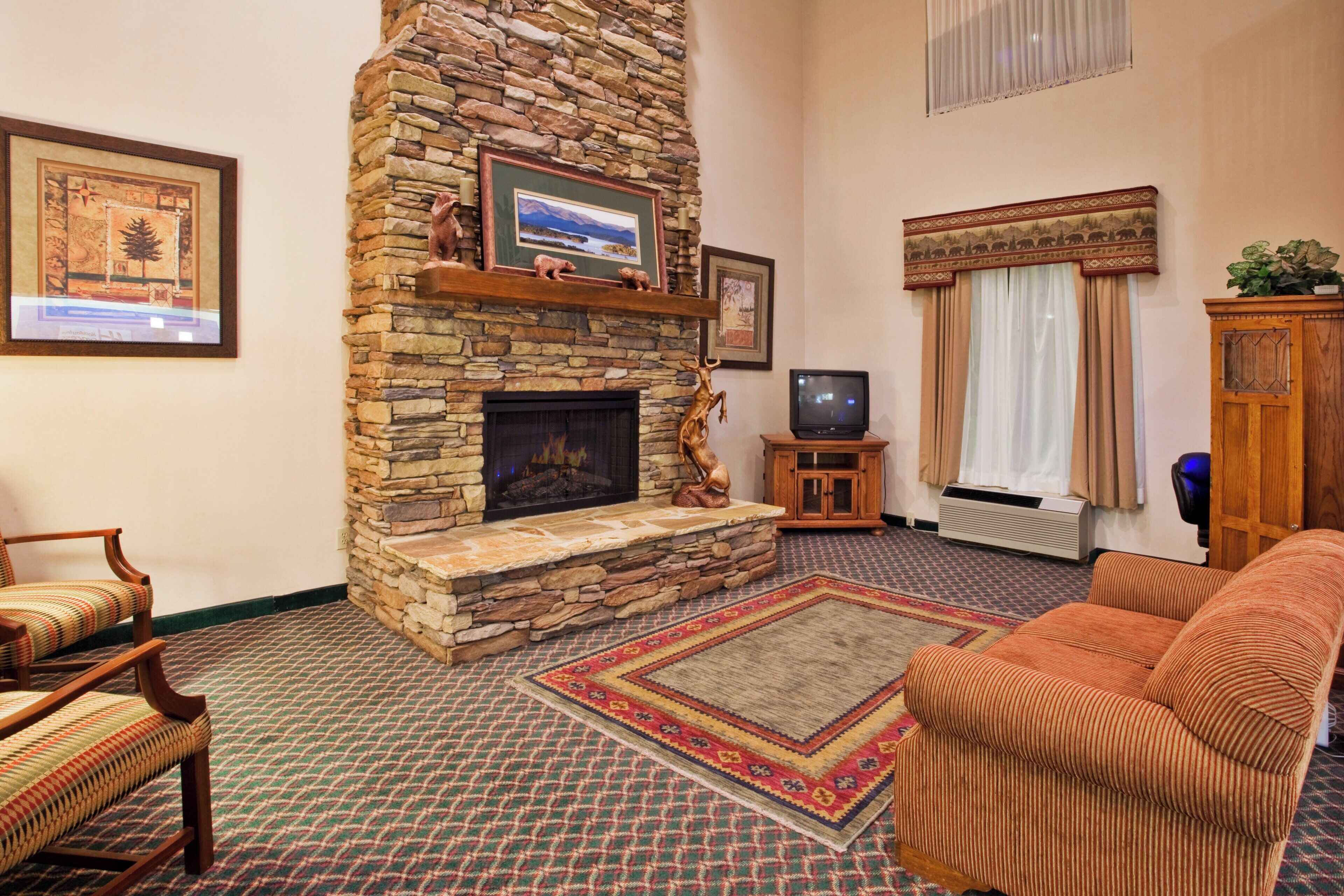 Una sala de estar con chimenea de piedra, un televisor y un sofá.