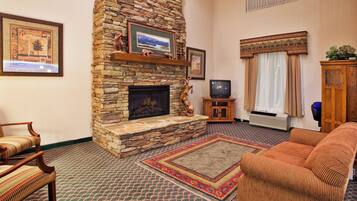 A living room with a stone fireplace, a television, and a sofa.