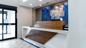 A reception desk with a modern design, a blue accent wall, and a glass display case. - Holiday Inn Express & Suites Hiawassee by IHG (Hiawassee)