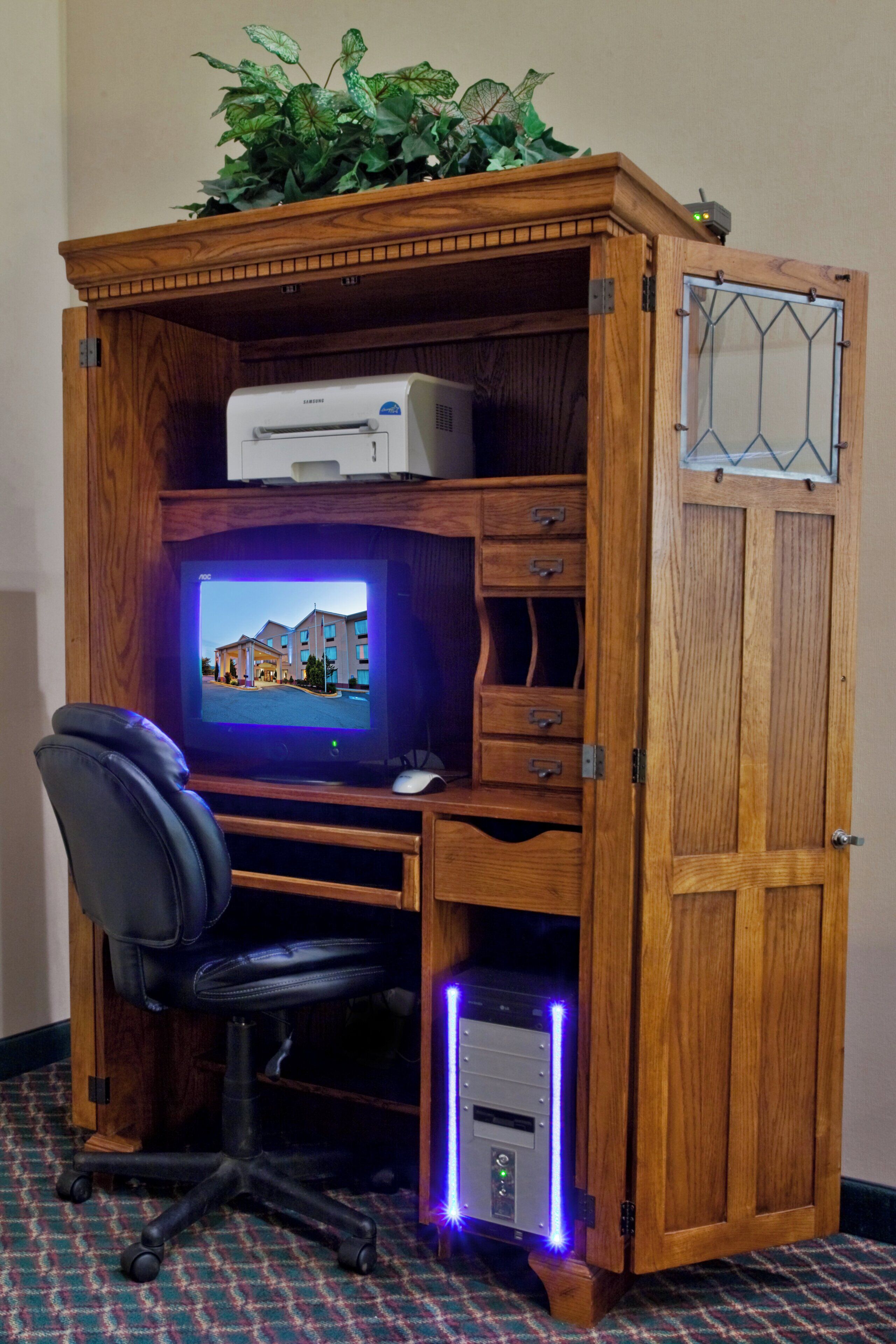 A wooden desk with a computer, a chair, and drawers.