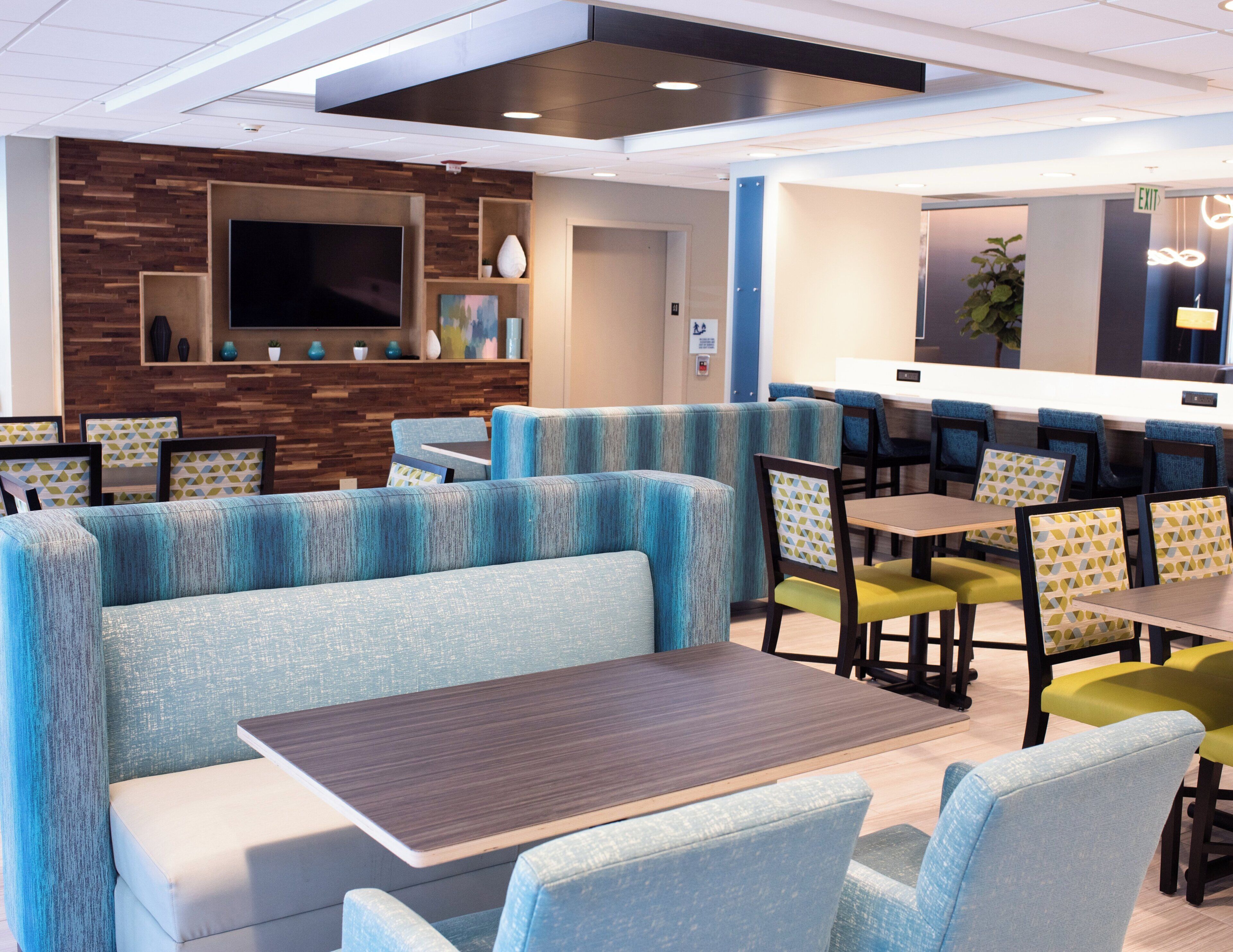 Un restaurant moderne avec des banquettes et des tables, un téléviseur à écran plat et un mur décoratif en bois.