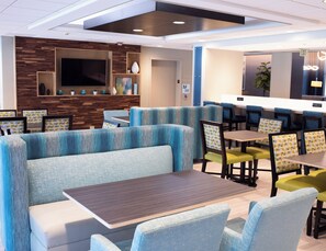 A modern restaurant with booths and tables, a flat-screen TV, and a wooden accent wall. - Holiday Inn Express Hotel & Suites Conover (Hickory Area) by IHG (Conover)