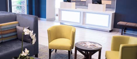 Un hall d’entrée avec un comptoir de réception, un espace salon et une plante sur une table.